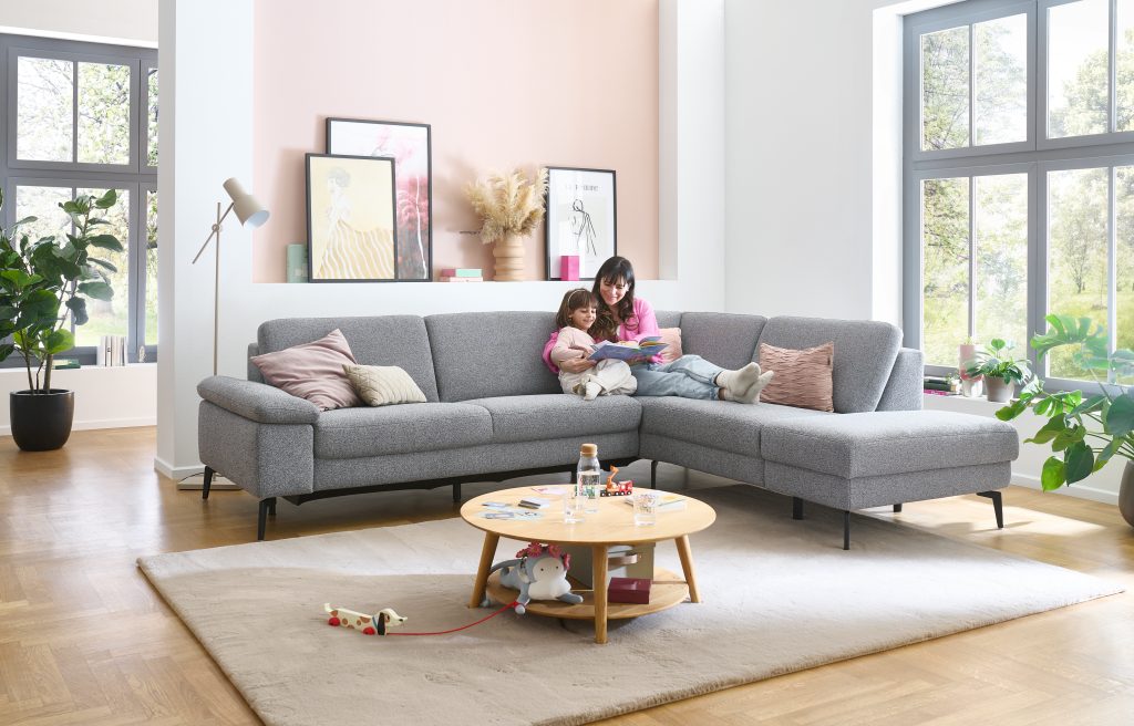 Familie auf einem grauen Ecksofa in einem hellen Wohnzimmer