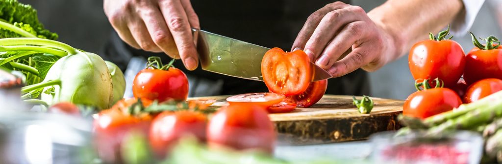Gemüse wird auf einem Holzbrett geschnitten