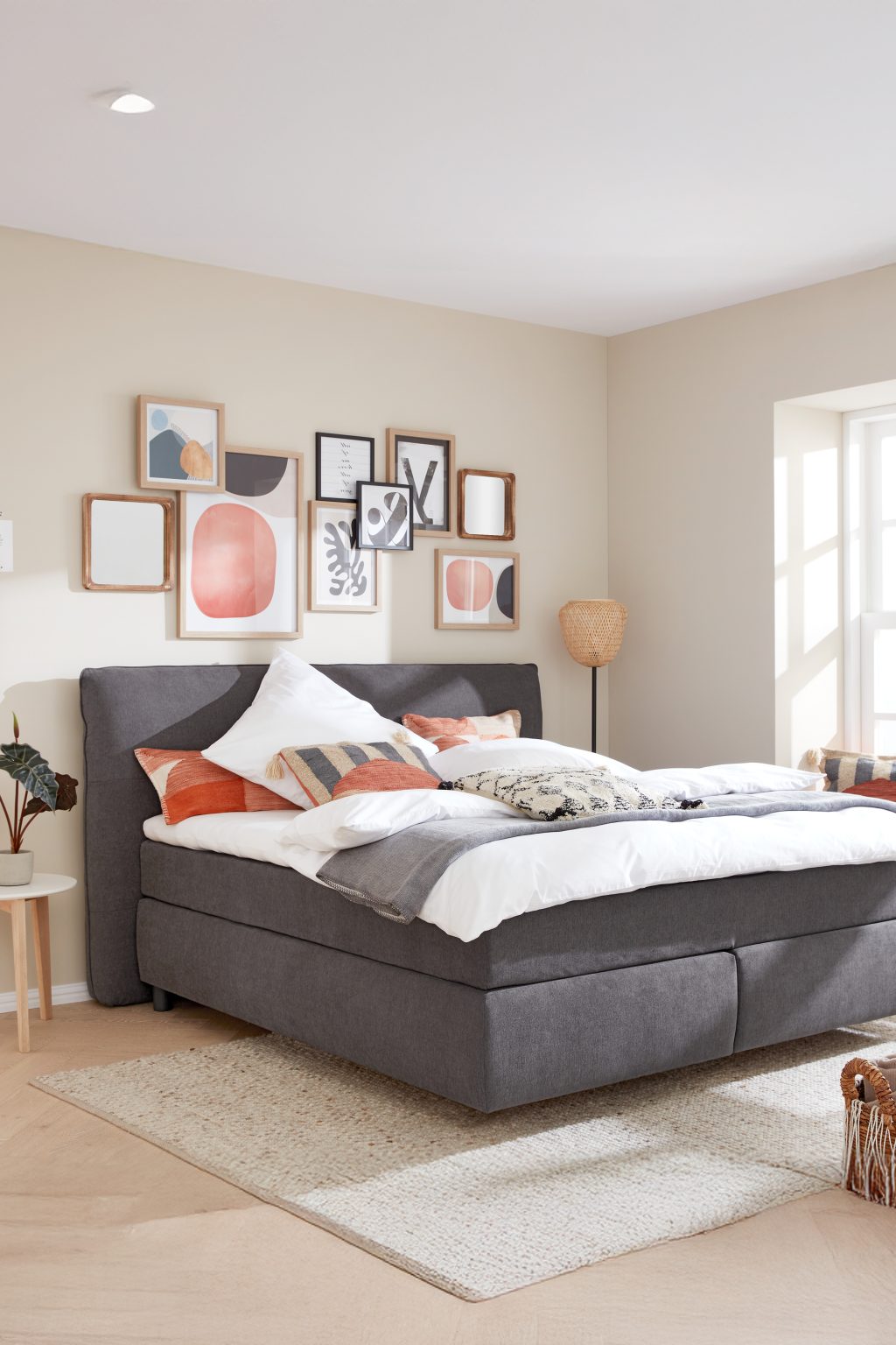 Boxspringbett mit gepolstertem Kopfteil unter einer Bilderwand