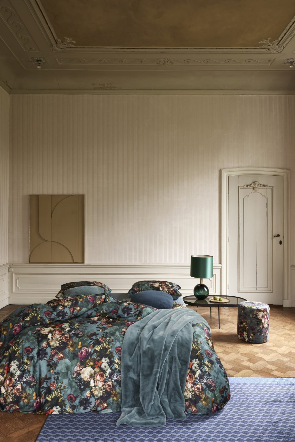Doppelbett mit gemusterter Bettwäsche in Blau und Grün in einem Altbauzimmer