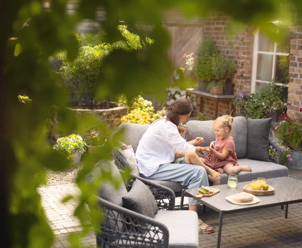 Vater und Kind frühstücken auf einer Gartenlounge hinter blühenden Zweigen