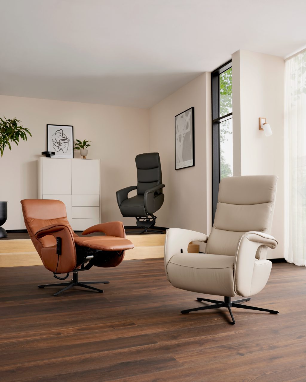 Zwei Relaxsessel in Cognac und Creme vor einer hellen Wohnwand