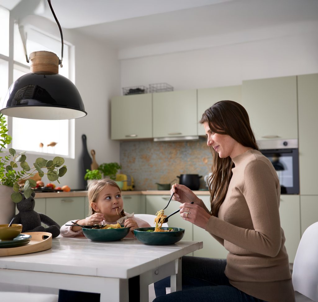 Mutter und Kind essen an der Küchentheke unter einer schwarzen Pendelleuchte