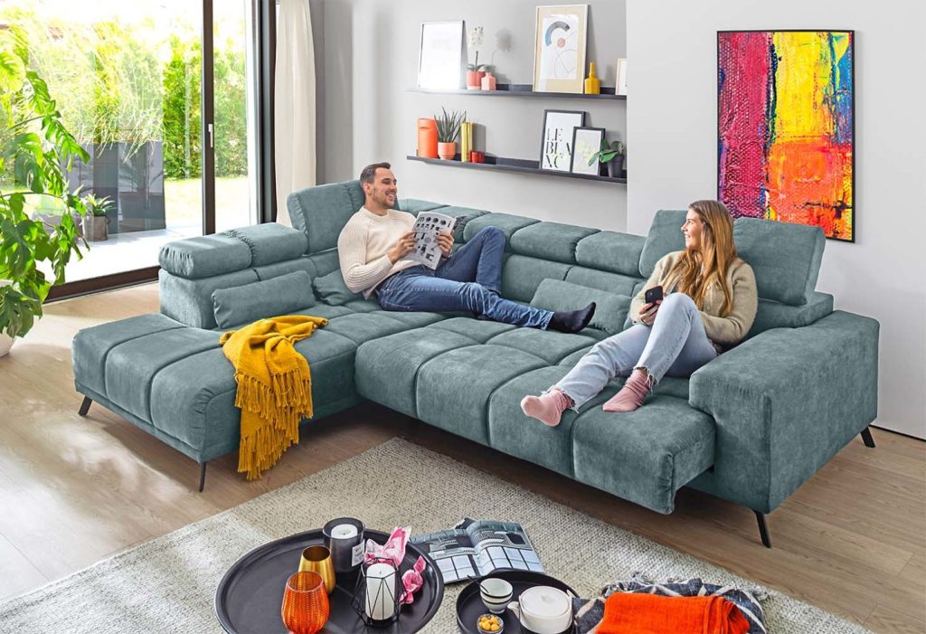 Wohnzimmer mit großem Ecksofa, zwei Menschen entspannen darauf