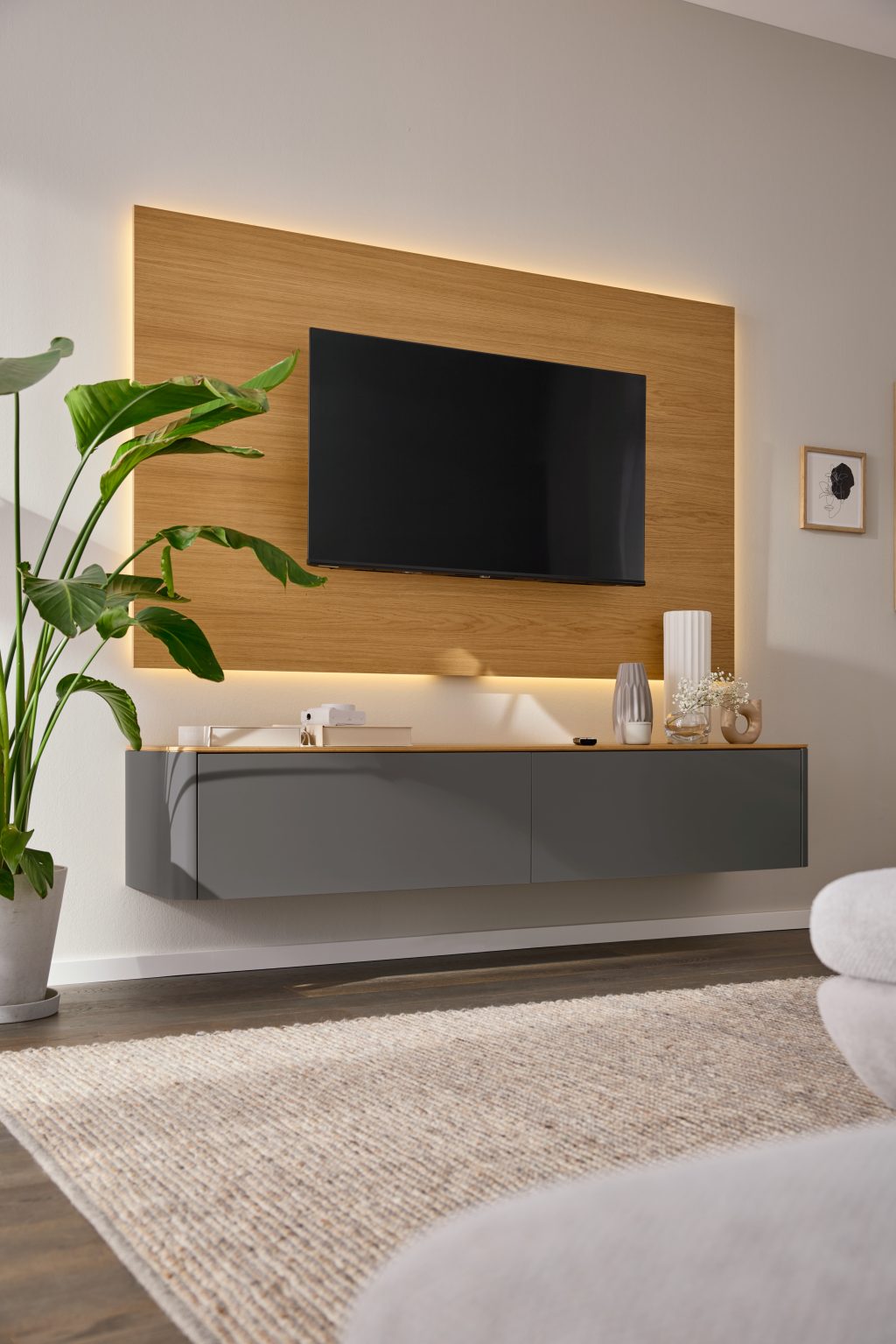 Wohnwand mit Fernseher in beleuchteter Holznische und grauem Lowboard